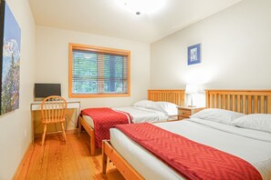 Ein Hotelzimmer mit zwei Betten, einem Schreibtisch, einem Stuhl, einem Fenster mit Jalousien und einem gerahmten Bild an der Wand.
