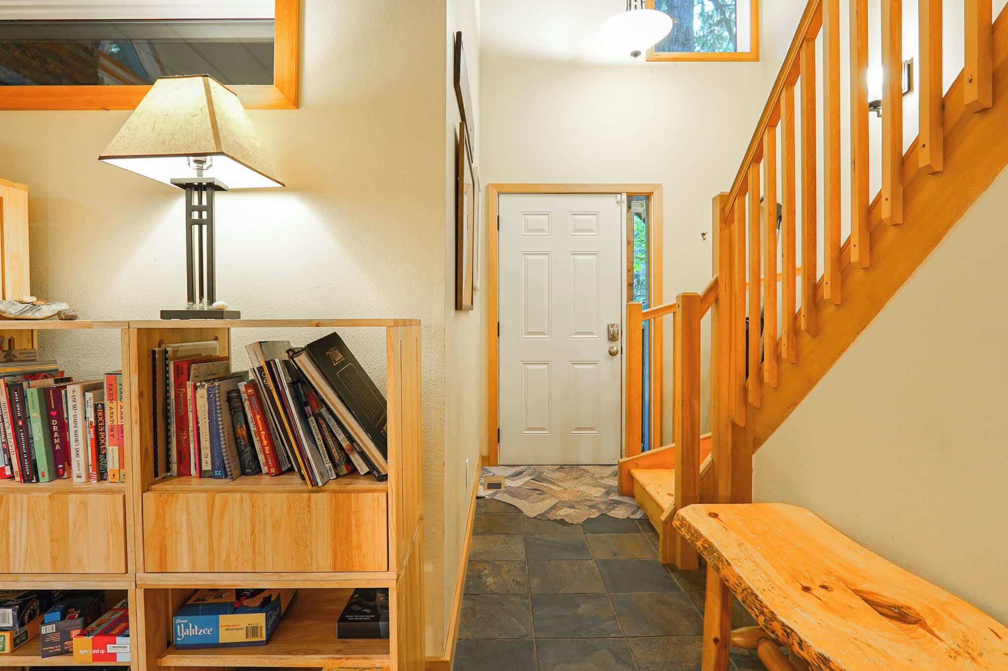 A wooden staircase leading to a door, a bookshelf with books, and a lamp.