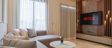 Una sala de estar moderna con un sofá modular, un televisor de pantalla plana y una mesa de centro redonda.
