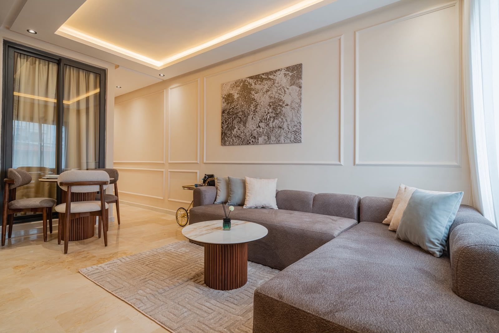 Una sala moderna con un sofá modular, una mesa de centro redonda y un comedor con sillas.