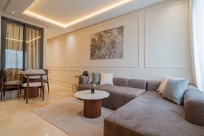 En moderne stue med en hjørnesofa, et rundt sofabord og et spiseområde med stole.