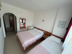 A hotel room with a double bed, a bedside table with a lamp, a mirror, a small bedside table with a remote control, and a picture on the wall. - Nice Hotel (Anamur)