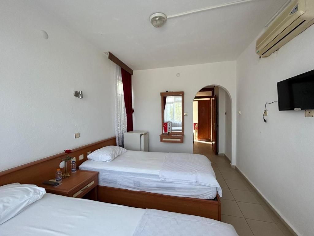 Une chambre d’hôtel avec deux lits, une télévision, un miroir et une porte donnant sur une autre pièce.