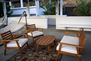 A patio area with wooden furniture, including chairs and a table, and a hammock.