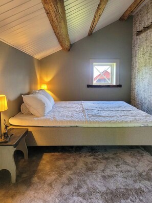A single bed with a headboard, a bedside lamp, and a small table with a figurine. - Converted barn with grass roof in Lindesby (Nora)