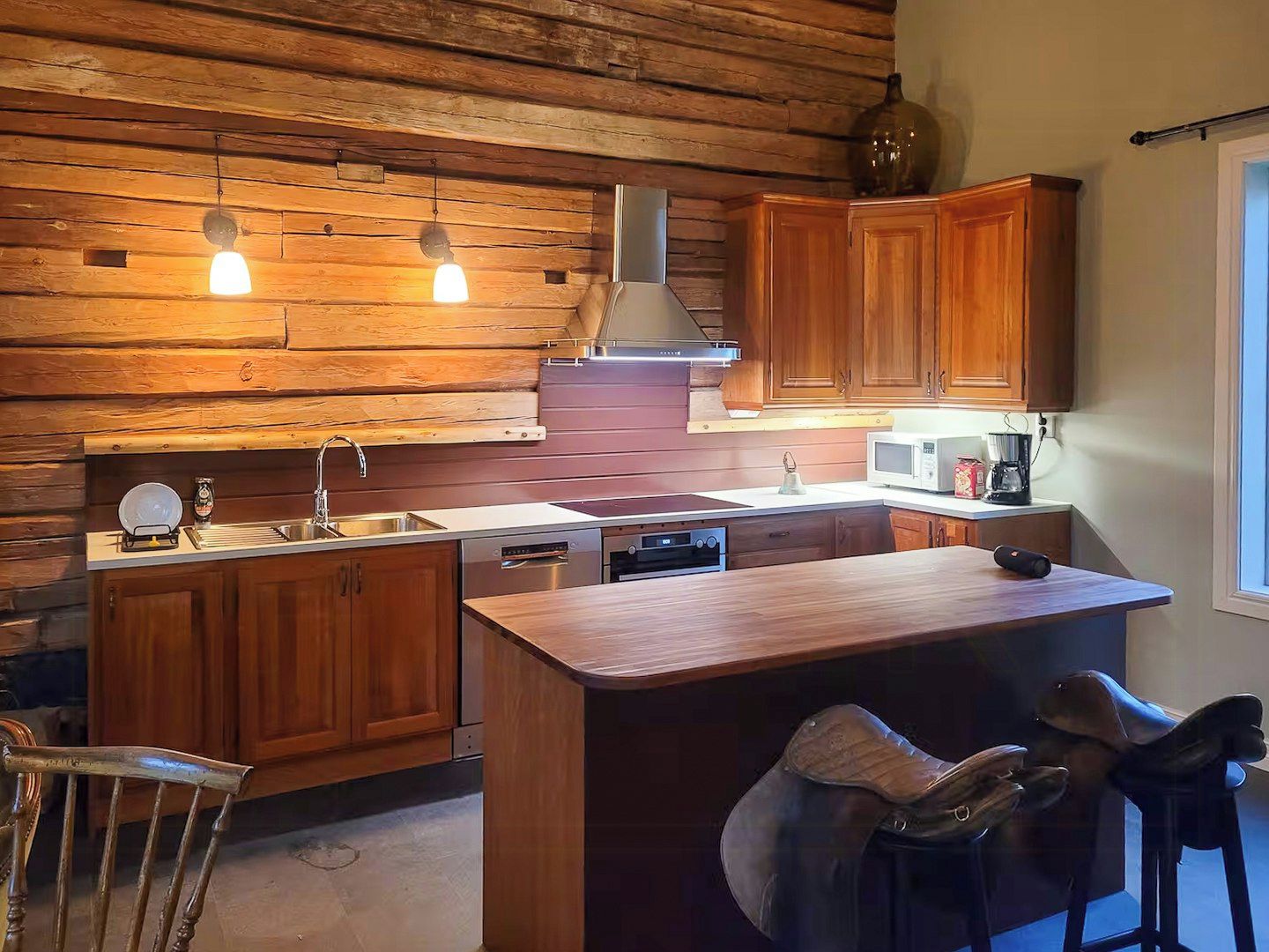 Una cocina con armarios de madera, una isla central, un horno empotrado y un microondas.