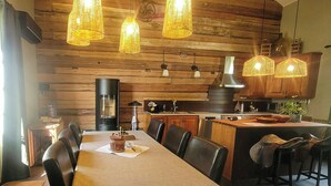 Un comedor con una mesa larga, sillas y lámparas colgantes.