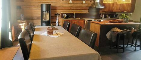 Un comedor con una mesa larga, varias sillas y lámparas de mimbre colgantes.