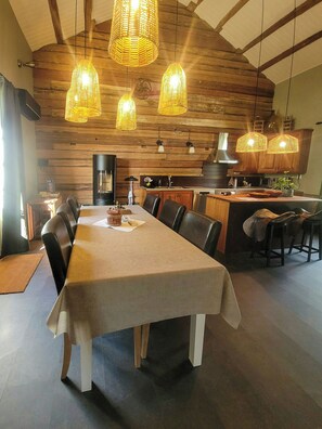 A dining area with a long table, chairs, and hanging light fixtures. - Converted barn with grass roof in Lindesby (Nora)