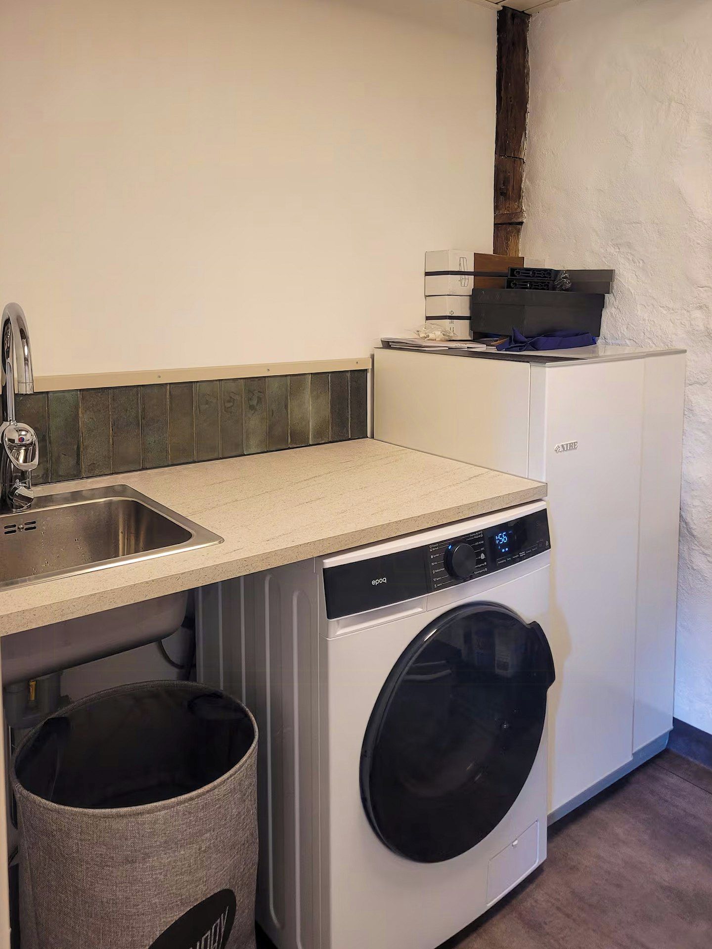 Een kleine keuken met een wasmachine, een spoelbak en een klein aanrecht.