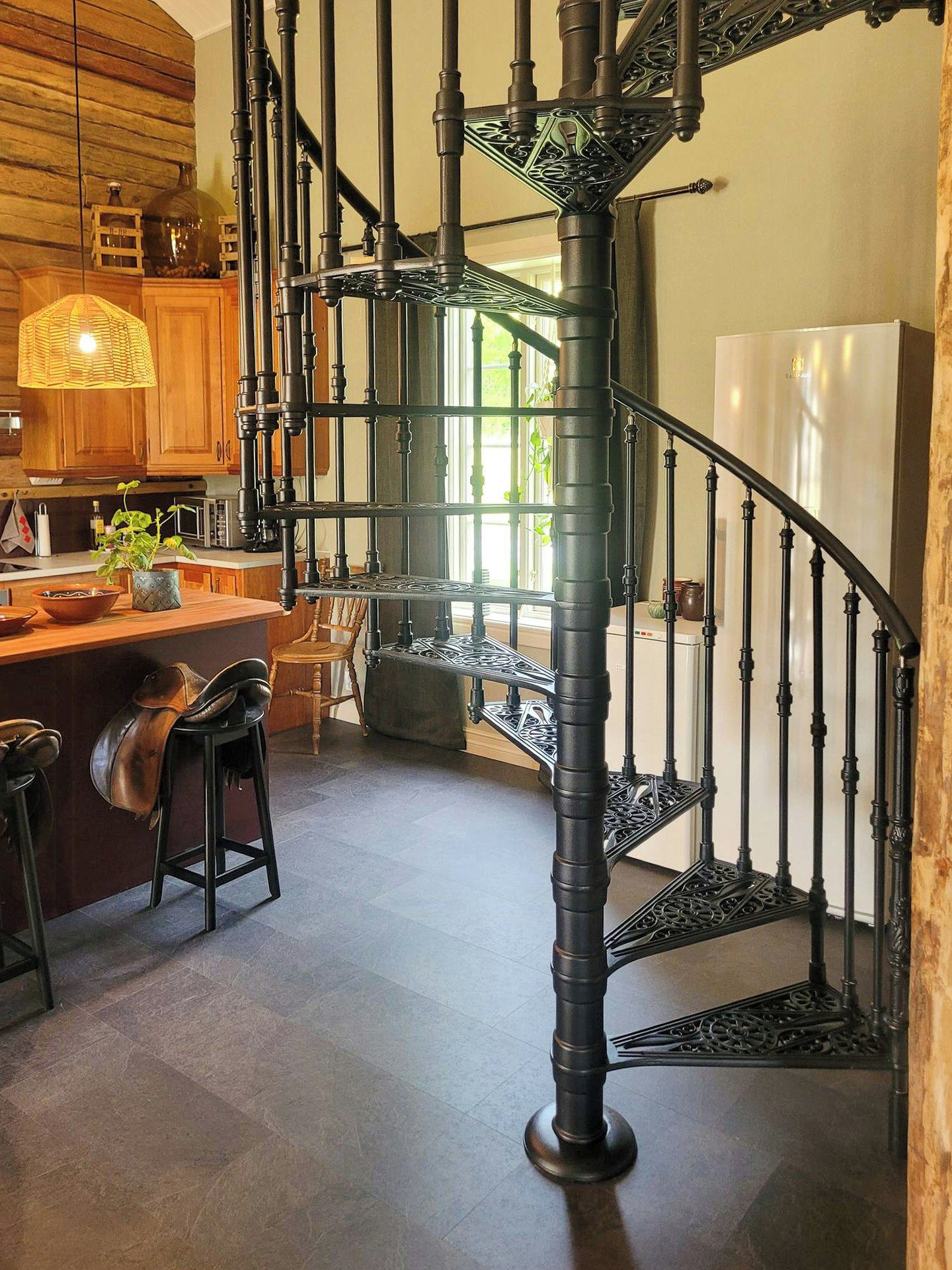 Un escalier en colimaçon avec une rampe métallique menant à un deuxième étage.