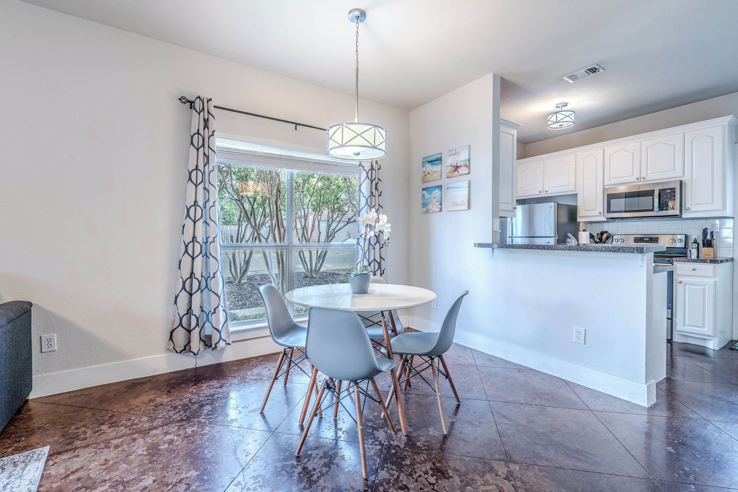 A modern kitchen with white cabinets, a built-in microwave, and a stainless steel refrigerator.
