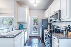 A modern kitchen with white cabinetry, stainless steel appliances, and a window overlooking a tree. - Spacious 3BR Downstairs Home Near TCU - Fort Worth (Fort Worth)