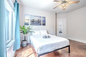 A bedroom with a bed, a potted plant, and two wall-mounted paintings. - Spacious 3BR Downstairs Home Near TCU - Fort Worth (Fort Worth)