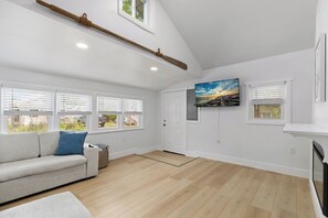 Ein geräumiges Wohnzimmer mit einem weißen Sofa, einem Kamin und einem großen Fenster mit Jalousien.
