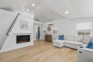 Ein modernes Wohnzimmer mit Kamin, einer Couch und einer Treppe.