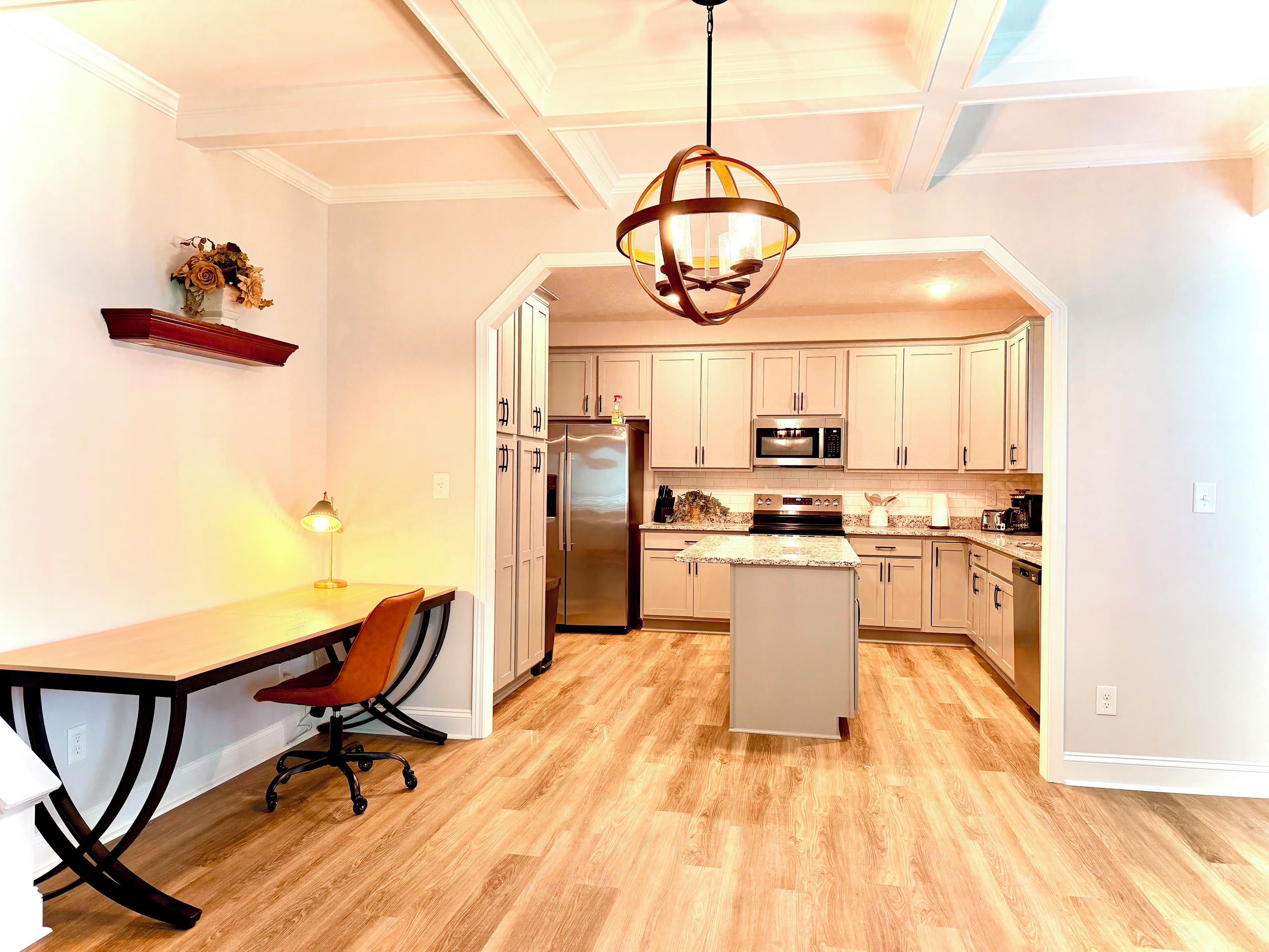 A modern kitchen with a central island, stainless steel appliances, and a pendant light.