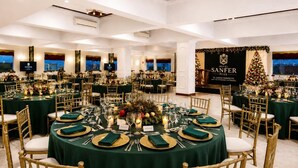 Un salón de banquetes con mesas redondas, sillas doradas y manteles verdes.