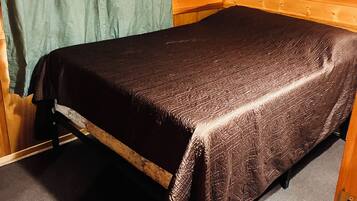 A single bed in a cabin with a wooden wall and a sign that says 'Life is better at the cabin.'