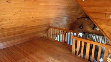 A wooden interior with a staircase, wooden walls, and a ceiling with a light fixture.
