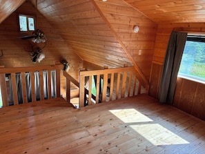 A wooden interior with a sloped ceiling, a staircase, and a window with curtains. - 1-bedroom cabin in Soldotna perfect for a cozy getaway near the Kenai River (Soldotna)