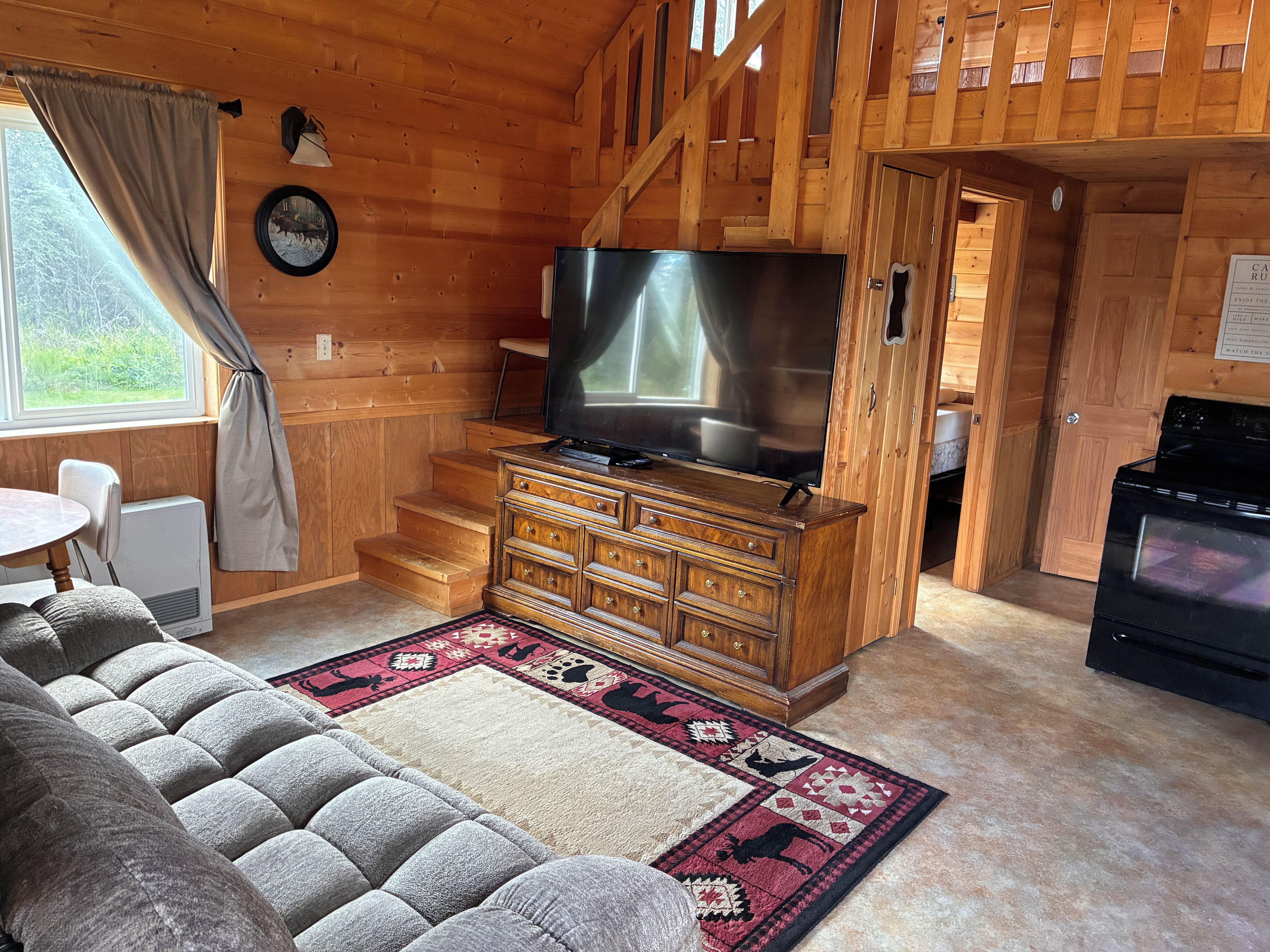 A wooden interior with a sofa, TV, and fireplace.