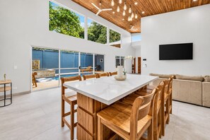 A modern kitchen with a large island, wooden chairs, and a dining table. - Casa Carlayna - tranquil villa in Potrero. Pool/Cool water Jacuzzi, WiFi, AC. (Potrero)