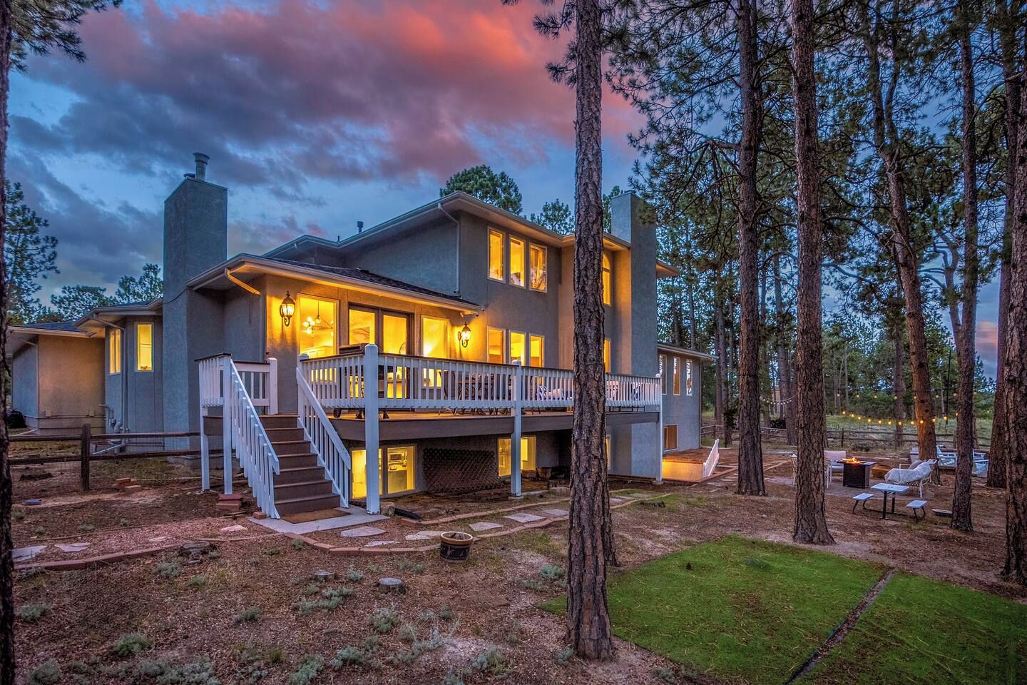 A two-story house with a balcony, surrounded by trees, and a well-maintained lawn.