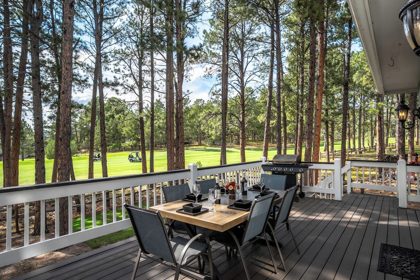 A deck with a table and chairs, overlooking a golf course.