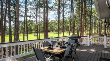A deck with a table and chairs, overlooking a golf course.