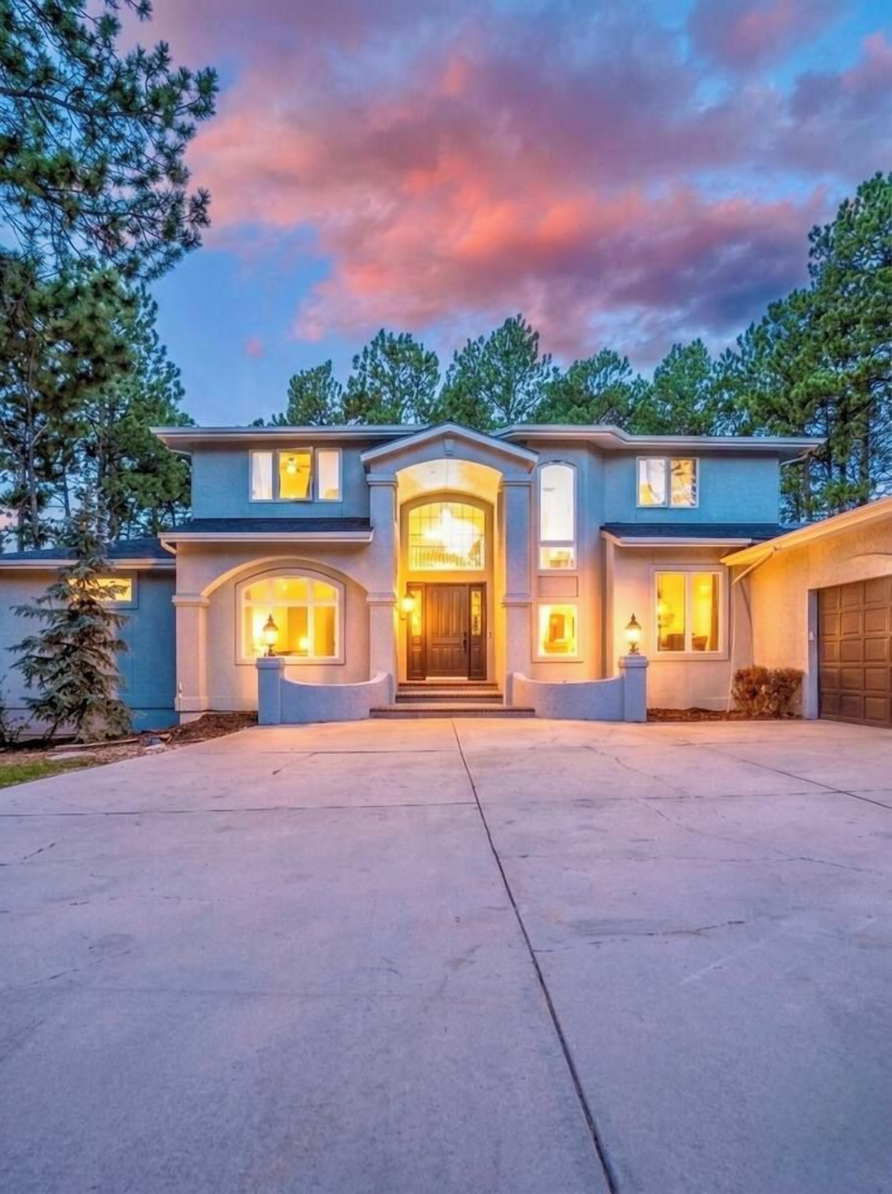 A two-story house with a central entrance, a garage on the right, and a driveway leading to the front door.