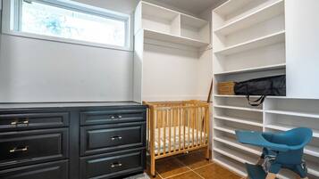 Habitación con cuna, cómoda y silla. Hay estantes con espacio de almacenamiento.