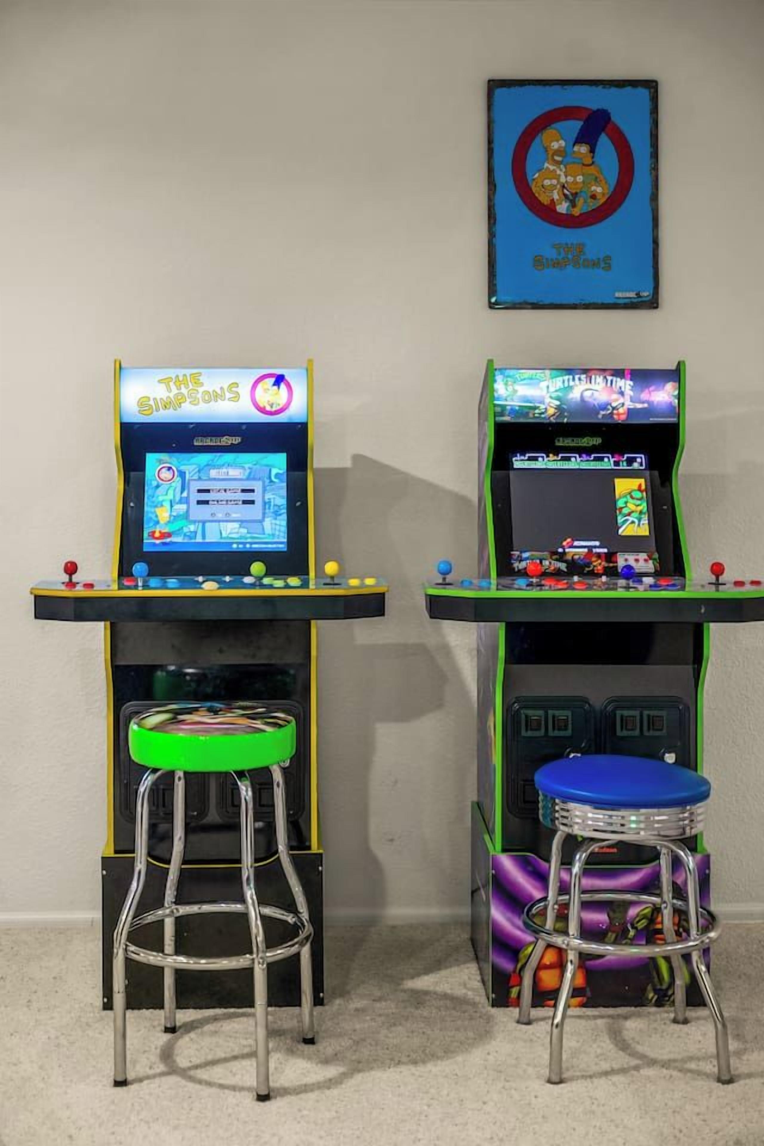 Two arcade machines with stools, one displaying 'The Simpsons' and the other 'Tetris.'