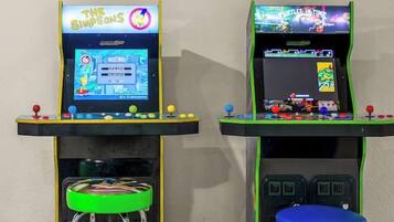 Two arcade machines with stools, one displaying 'The Simpsons' and the other 'Tetris.'