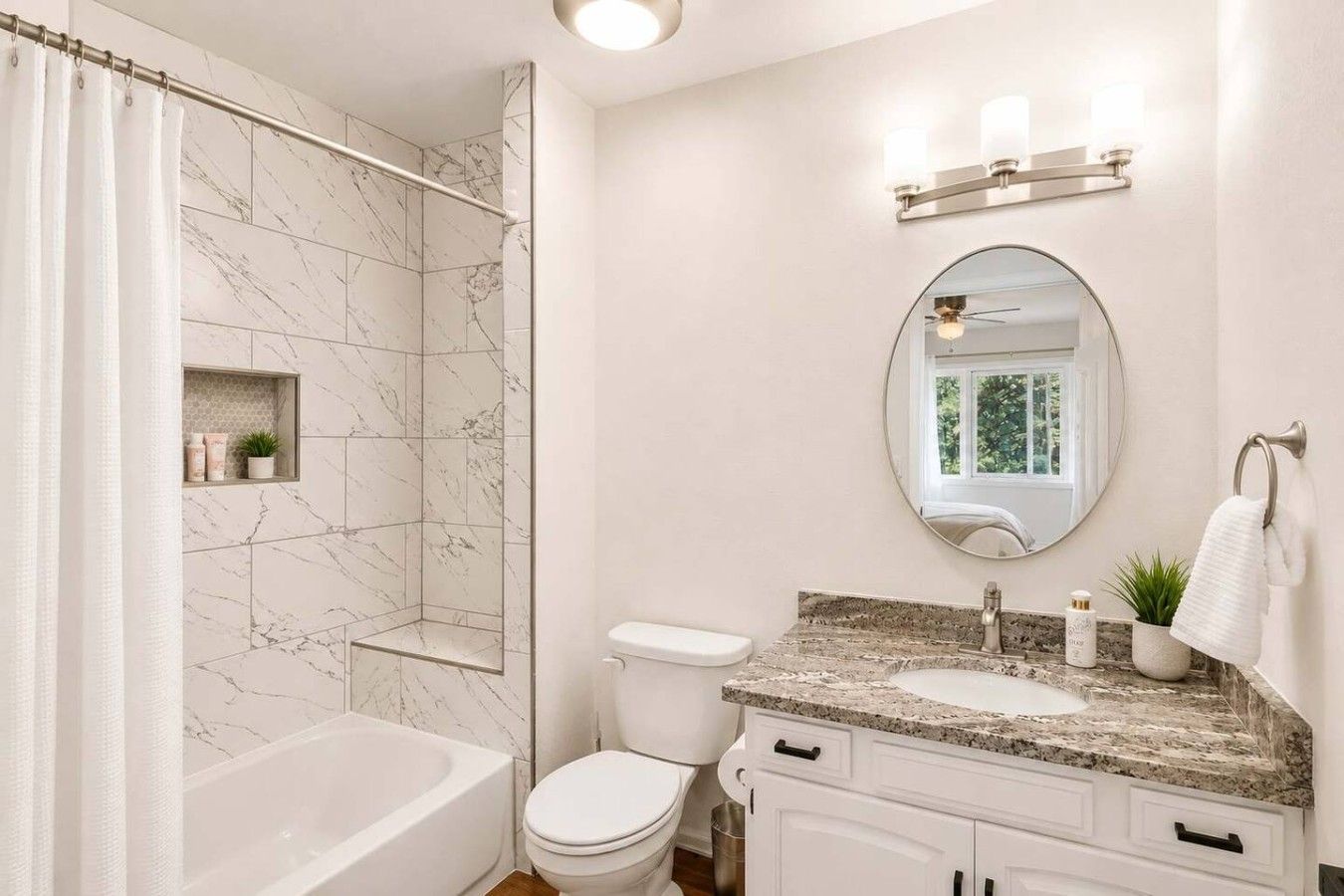 A bathroom with a bathtub, toilet, vanity with a sink, and a shower area.