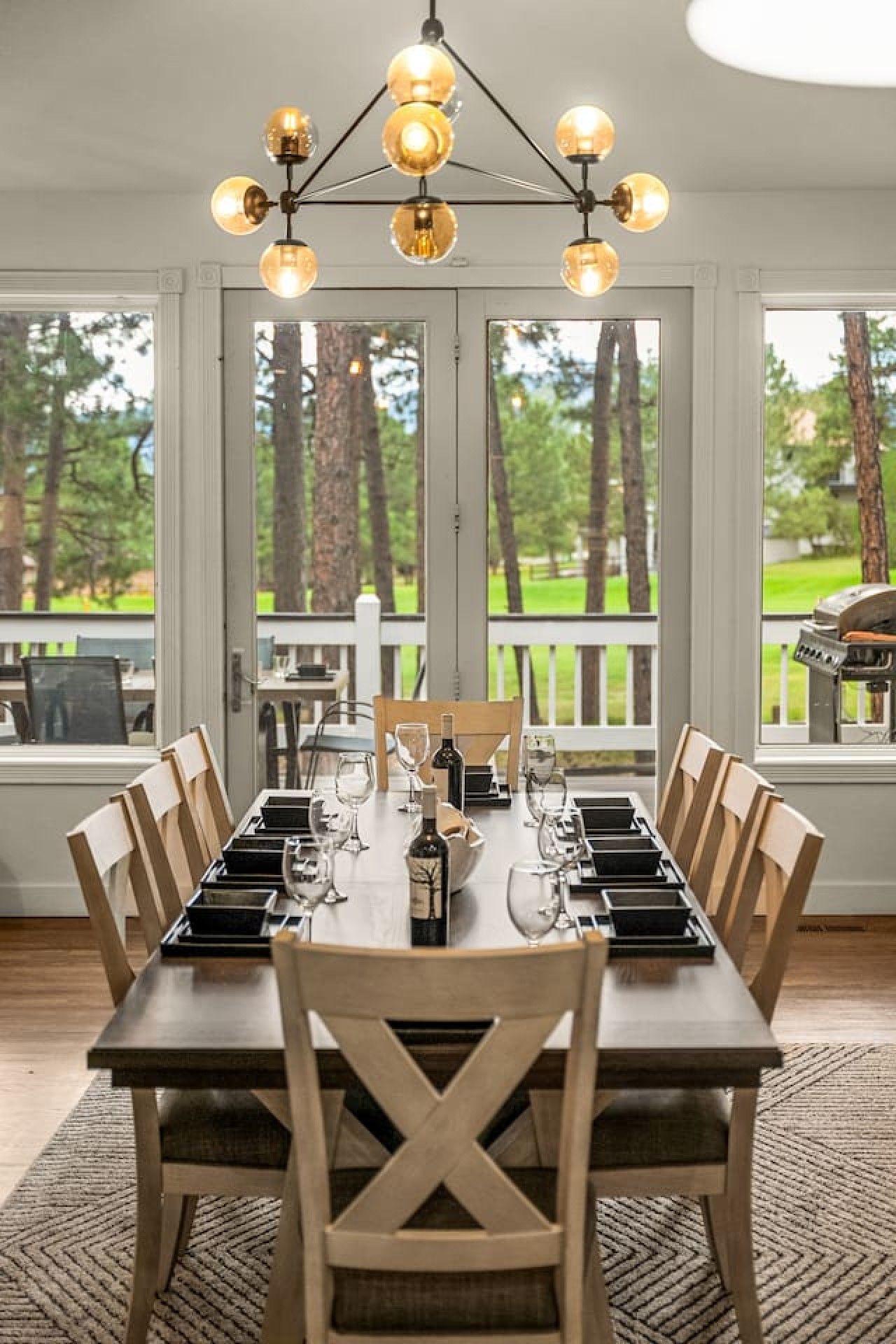 Comedor con una larga mesa dispuesta para seis personas, rodeada de sillas y un candelabro colgante.