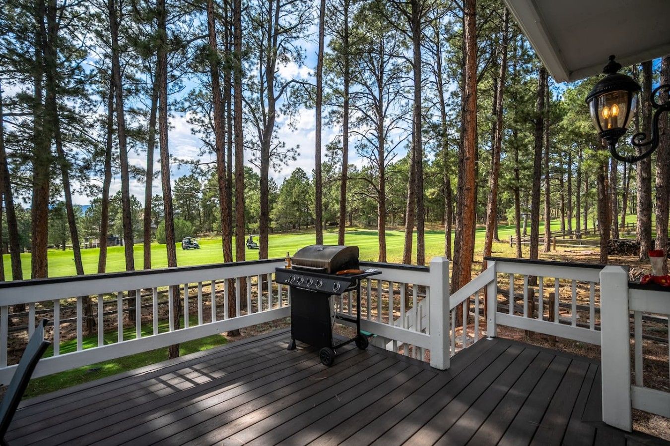 Terraza de madera con una parrilla, con vistas a un campo de golf.