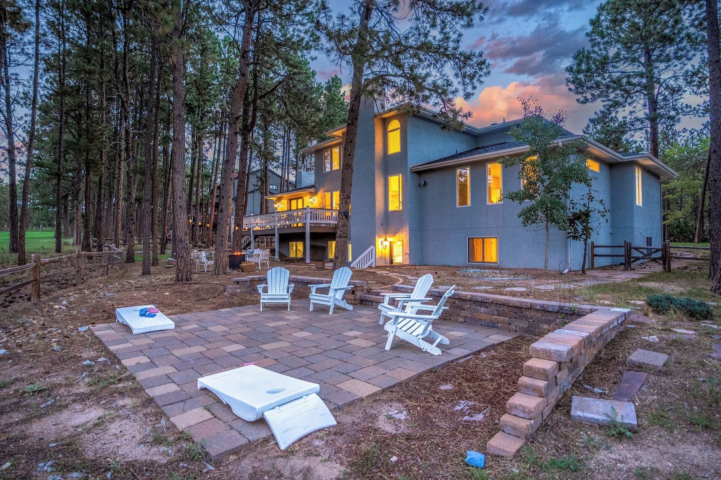 A two-story house with a patio area, surrounded by trees.