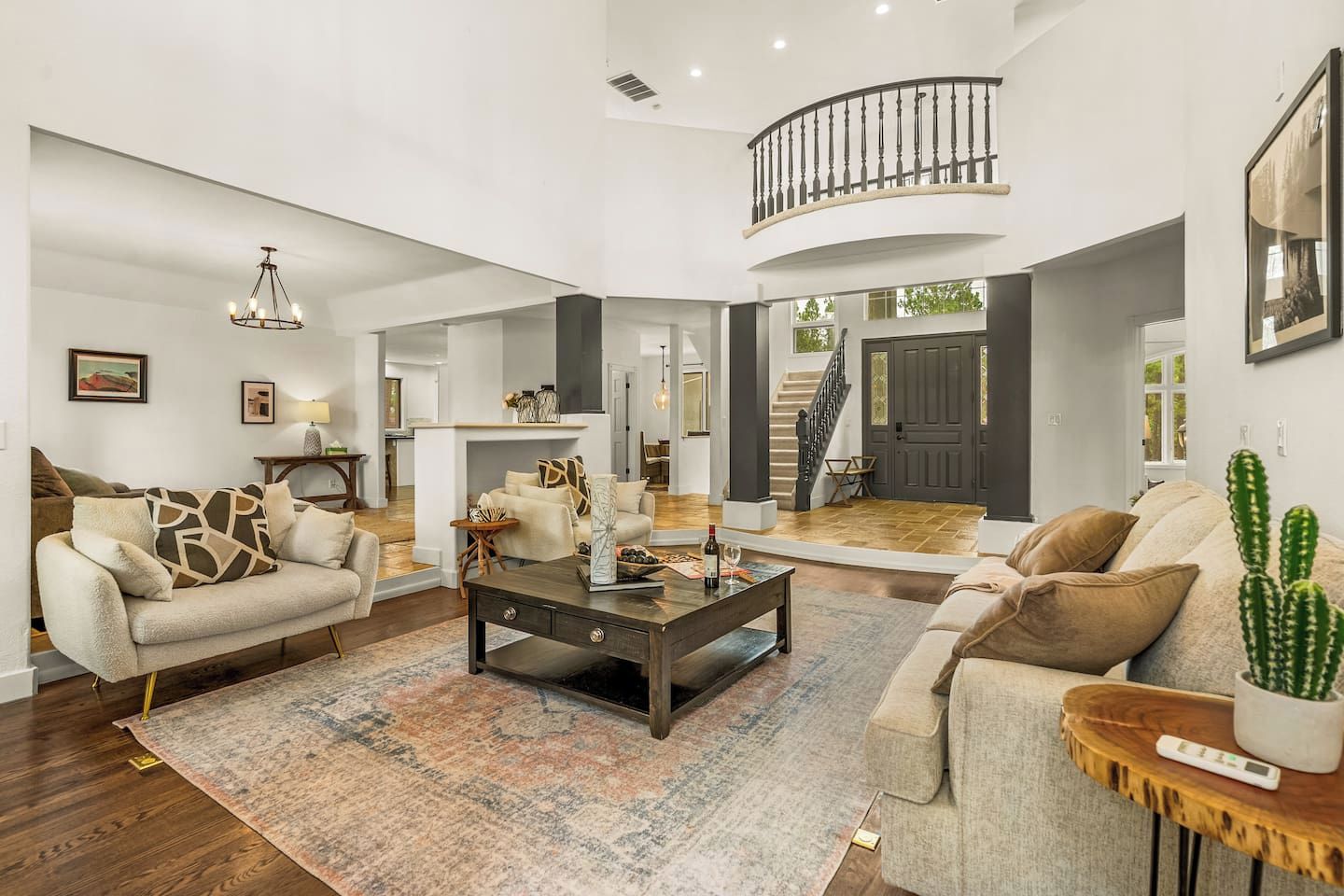 A spacious living room with a fireplace, a coffee table, and two sofas. A staircase is visible in the background.