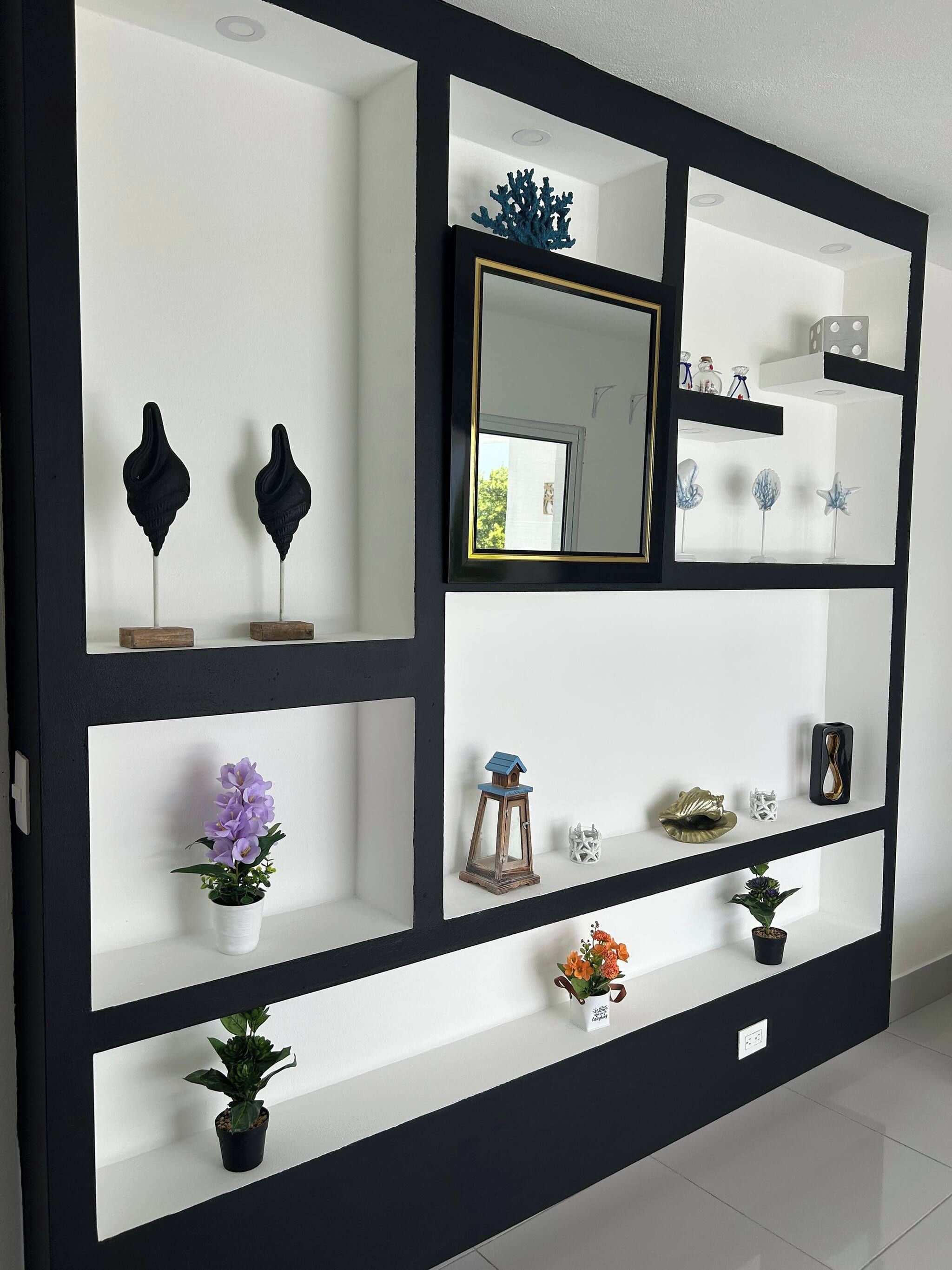 Una pared con varias estanterías exhibiendo diversos objetos decorativos.