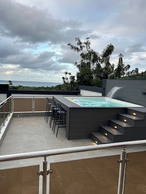 A rooftop terrace with a hot tub, bar stools, and a view of the ocean. - Luxurious Villa Retreat With Private Pool in Villa Vásquez (Villa Vásquez)