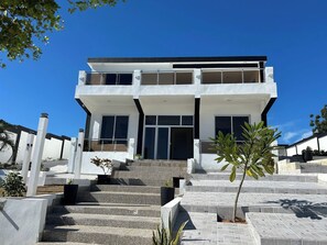A modern two-story building with a flat roof, large windows, and a staircase leading to the entrance. - Luxurious Villa Retreat With Private Pool in Villa Vásquez (Villa Vásquez)