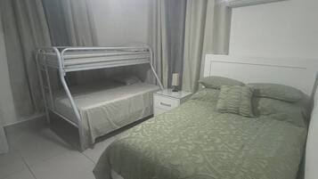 A bedroom with a bunk bed, a single bed, a nightstand, and a ceiling fan.