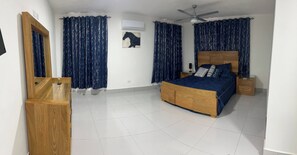 A bedroom with a bed, a wooden wardrobe, a ceiling fan, and a wall-mounted air conditioner. - Luxurious Villa Retreat With Private Pool in Villa Vásquez (Villa Vásquez)