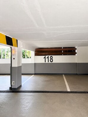 Eine Parkgarage mit Betonboden, einem Schild mit der Nummer 118 und einer gelb-schwarz gestreiften Wand.