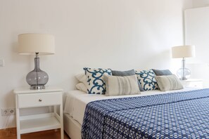 A bedroom with a bed, two bedside tables, and a lamp on each.