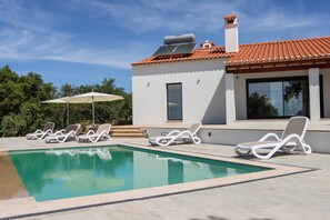 A modern house with a swimming pool, white walls, and a red-tiled roof.