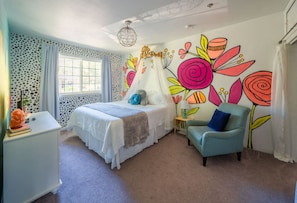 A bedroom with a bed, a chair, a nightstand, a wall mural, and a window. - Treehouse - Sleeps 14, Hot Tub, 2-Story Solarium (Sioux Falls)