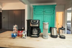 A kitchen counter with a coffee maker, a kettle, a coffee pot, a French press, and a coffee grinder. - Treehouse - Sleeps 14, Hot Tub, 2-Story Solarium (Sioux Falls)