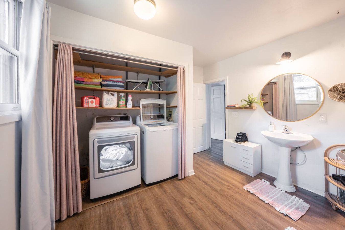 A laundry room with two washing machines, a drying rack, and a shelf with cleaning supplies.